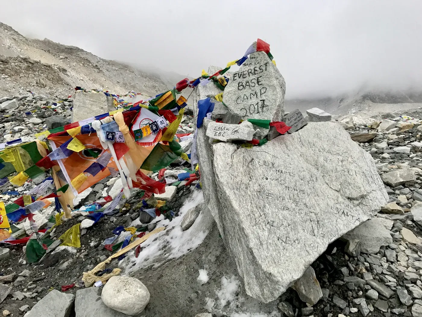 Trekker at Everest Base Camp with helicopter hovering above the Khumbu glacier